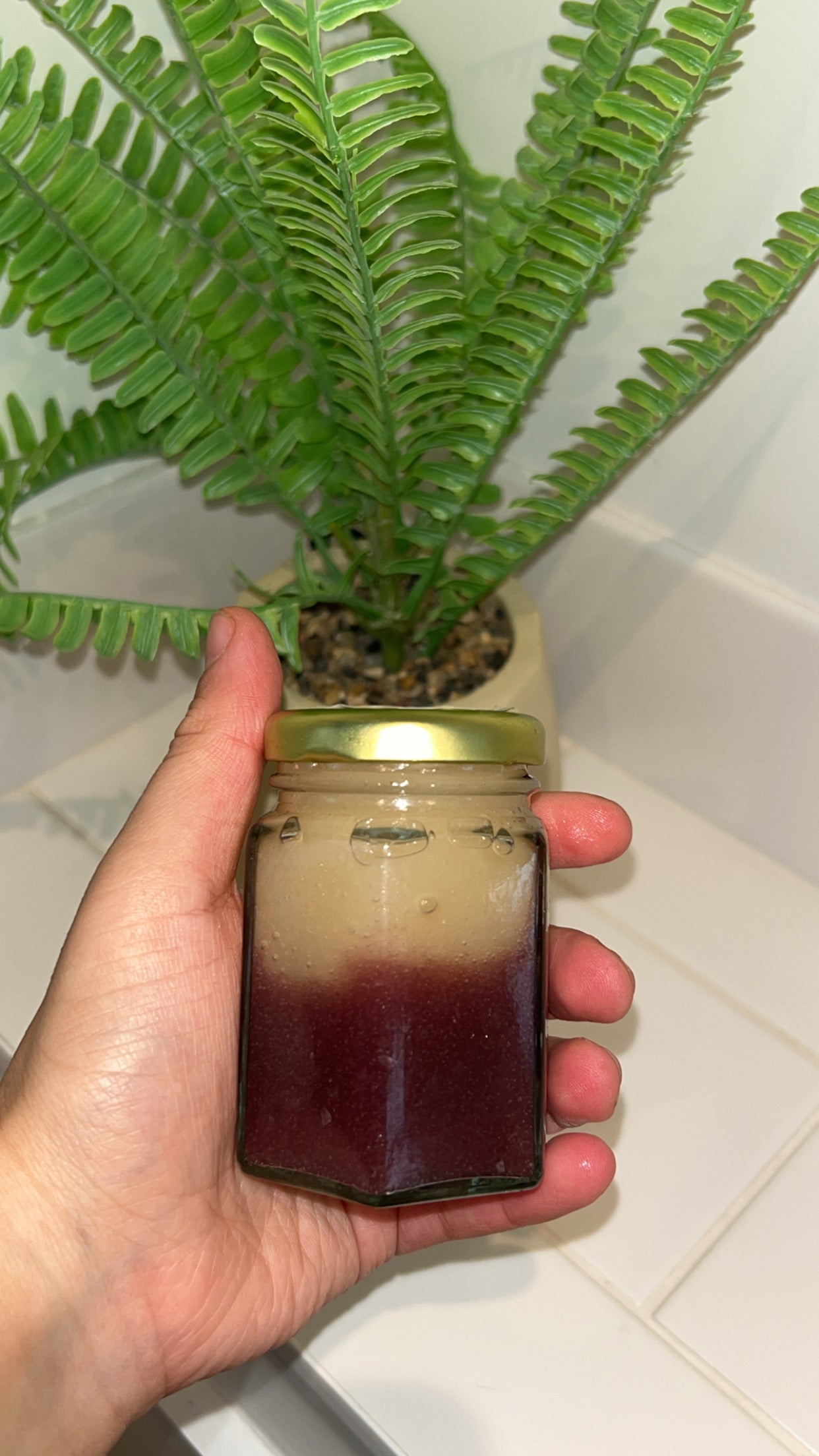110ml Organic Sea Moss gel. Front shot. Lady holding it in her hand behind a plant