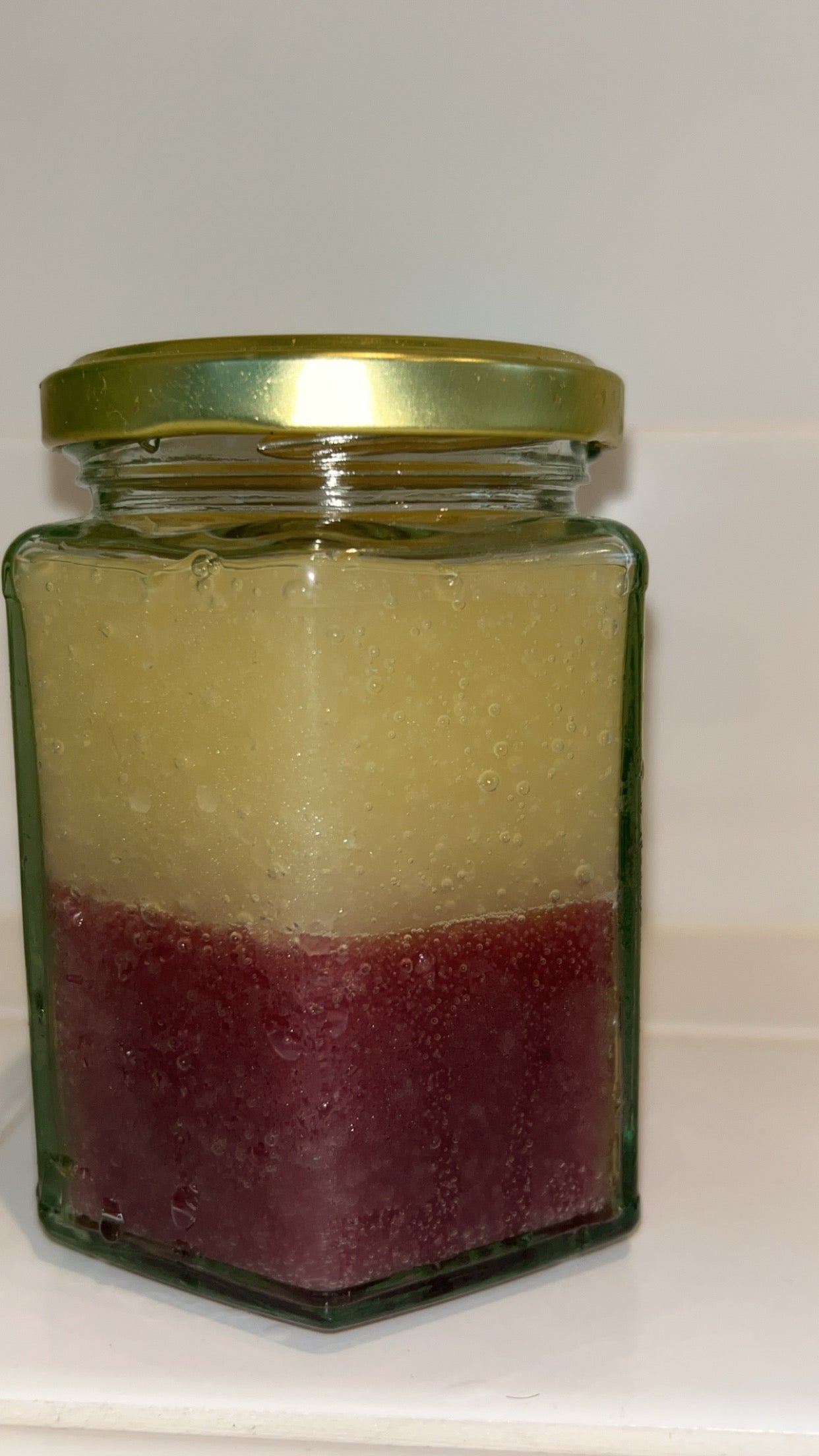 280ml Organic Puple and golSea Moss gel. Front shot. Lady holding it in her hand behind a plant